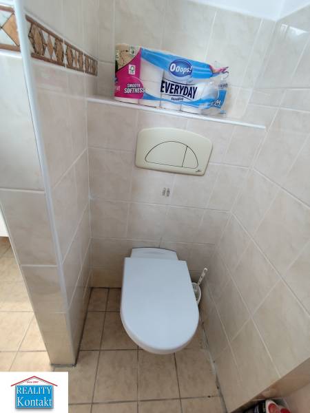 Na prenájom 2-izbový byt  Nové Zámky - Záchodová miestnosť v 2-izbovom byte s obkladmi a toaletným papierom na poličke.