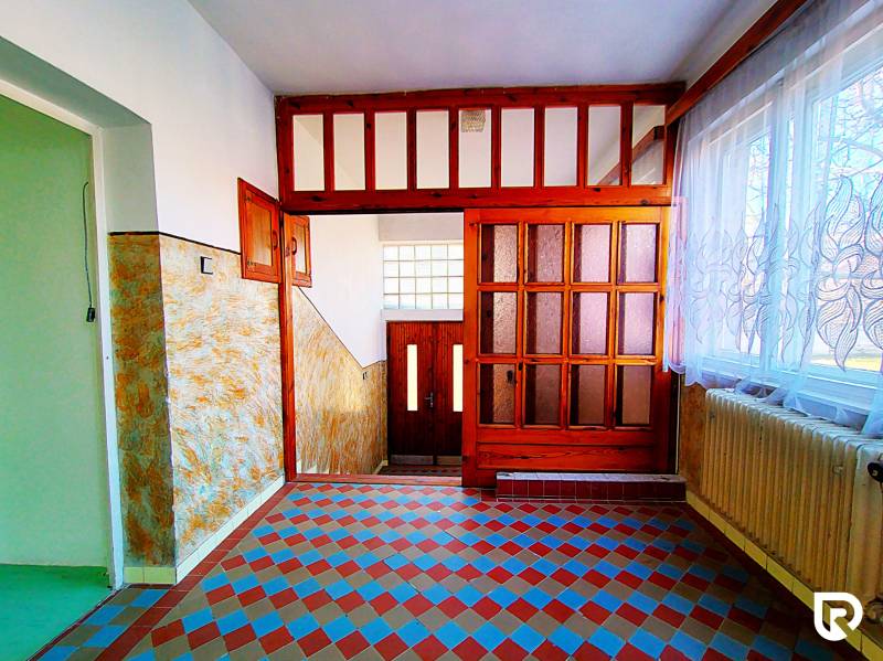 Rodinný dom v obci Borskom Mikuláš. - Chodba v rodinnom dome s dlažbou s farebným vzorom, drevenými dverami a záclonami.