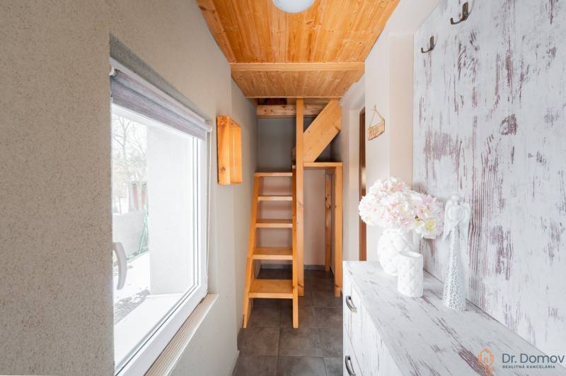 Záhradná chatka Handlová - Interiér chaty s dreveným schodiskom a oknom s výhľadom na exteriér.