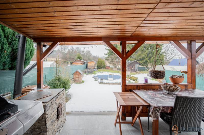 Záhradná chatka Handlová - Drevený prístrešok pri chate v Handlovej, s výhľadom na zasneženú záhradu a ploty.