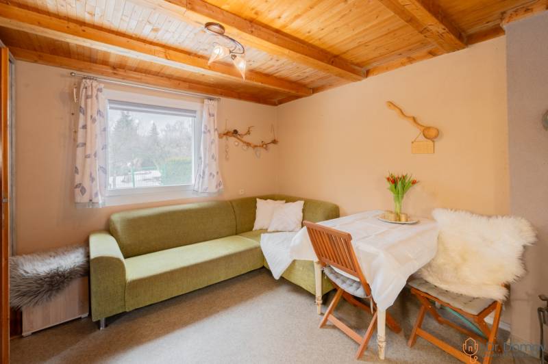 Záhradná chatka Handlová - Interiér chaty s rohovej sedačkou, stolom a dreveným stropom.