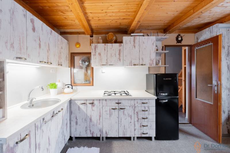 Záhradná chatka Handlová - Kuchyňa v chate s dreveným stropom a vintage skriňami, útulné vybavenie.