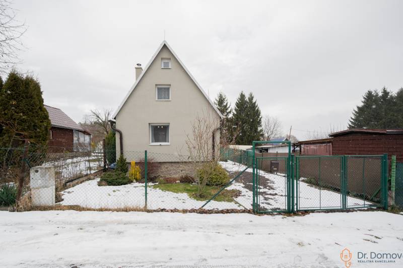 Záhradná chatka Handlová - Chata v Handlovej s trochou snehu na dvore, obklopená zeleňou a plotom.