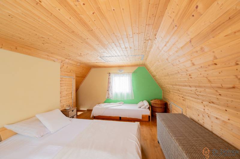 Záhradná chatka Handlová - Priestor v Chate s dreveným obložením, posteľami a podlahou s dreveným dekorom.