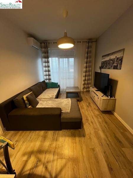 Predáme 2 izb byt v novostavbe v Senci  - Obývačka v 2-izbovom byte s pohodlnou sedačkou a podlahou s dreveným dekorom.