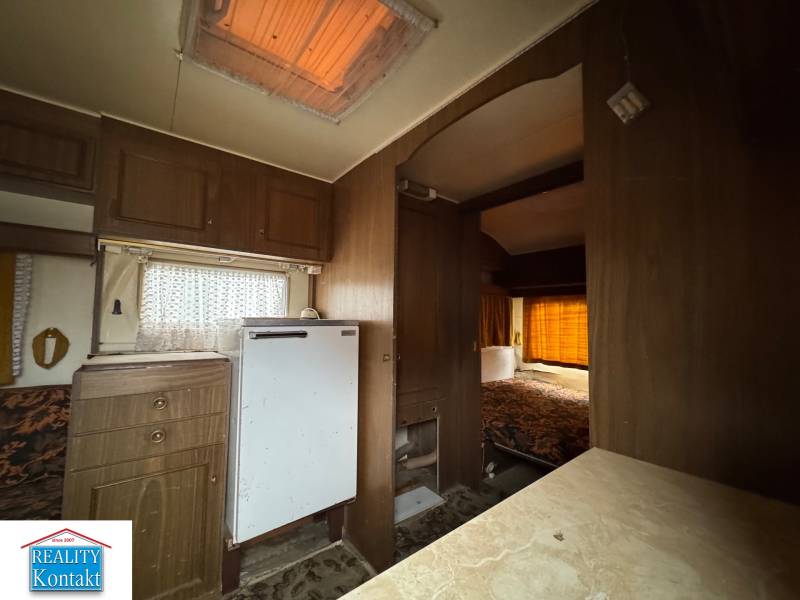 Predám pozemok v obci Dubník okr. Nové Zámky - Interiér s podlahou s dreveným dekorom, kuchynskou linkou a posteľou v Pozemky - bývanie.