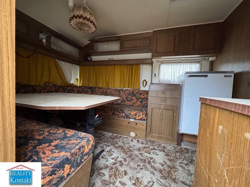 Predám pozemok v obci Dubník okr. Nové Zámky - Interiér obytného priestoru s kobercovou podlahou, sedací súpravou a stolom.