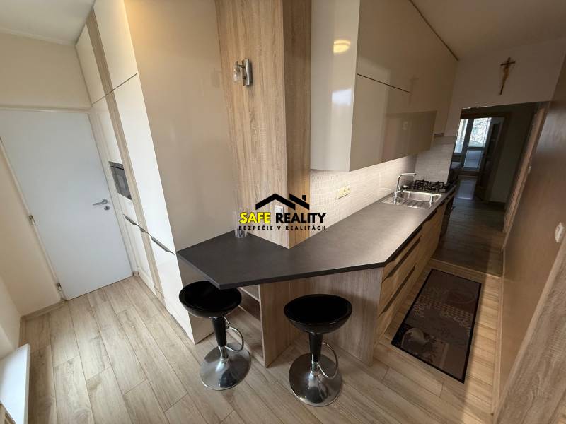 PRENÁJOM Trojizbový zariadený byt, Žilina - Vlčince - Kuchyňa v 3-izbovom byte s podlahou s dreveným dekorom a jedálenským pultom.