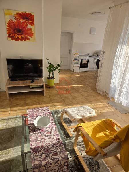 Viacgeneračný rodinný dom / investičná nehnuteľnosť – Dolná časť Zobor - Obývacia izba v rodinnom dome so sedačkou, televízorom a pohľadom na kuchyňu.