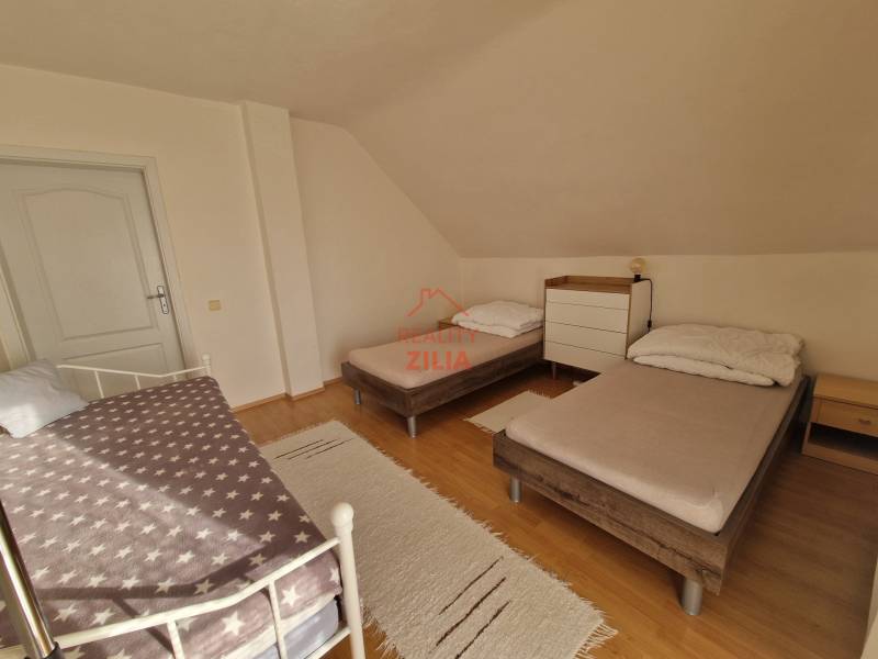 Viacgeneračný rodinný dom / investičná nehnuteľnosť – Dolná časť Zobor - Spálňa v rodinnom dome s tromi posteľami a podlahou s dreveným dekorom.