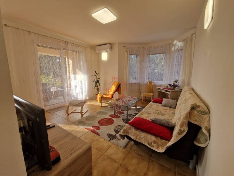 Viacgeneračný rodinný dom / investičná nehnuteľnosť – Dolná časť Zobor - Obývačka rodinného domu s televízorom, pohovkou, stolíkom a veľkými oknami s závesmi.