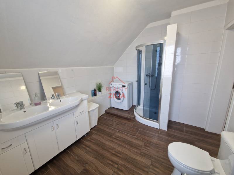 Viacgeneračný rodinný dom / investičná nehnuteľnosť – Dolná časť Zobor - Kúpeľňa v rodinnom dome s umývadlom, sprchovým kútom a podlahou s dreveným dekorom.