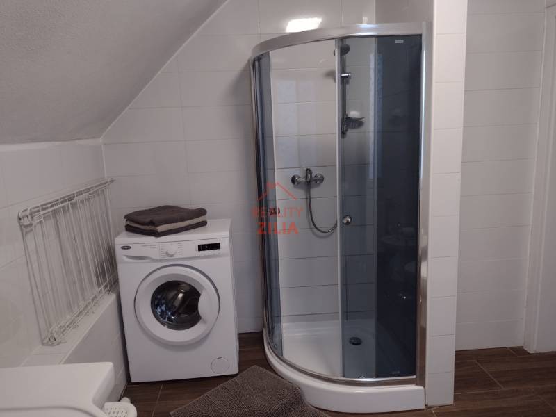 Viacgeneračný rodinný dom / investičná nehnuteľnosť – Dolná časť Zobor - Kúpeľňa v rodinnom dome s práčkou, sprchovým kútom a podlahou s dreveným dekorom.