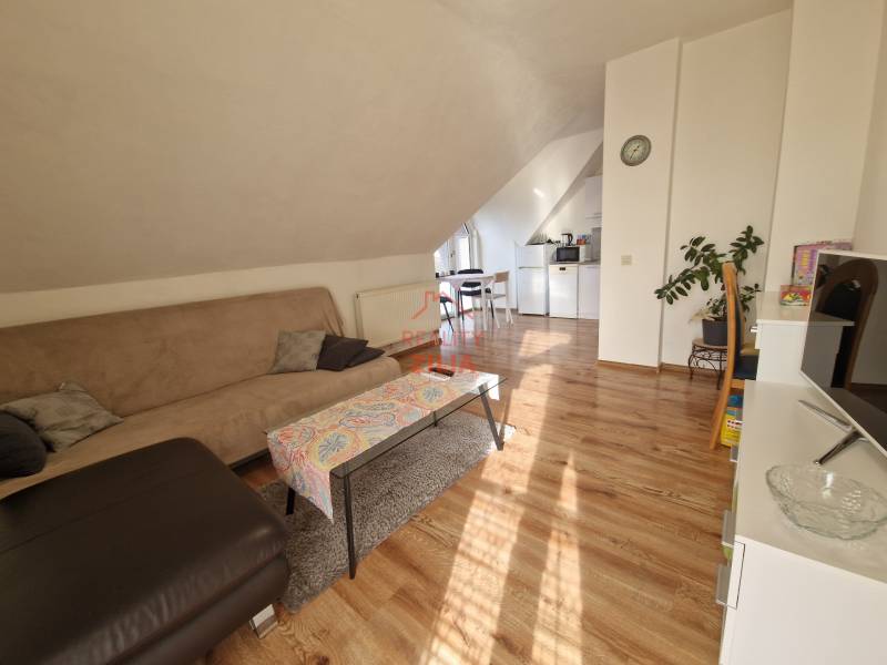 Viacgeneračný rodinný dom / investičná nehnuteľnosť – Dolná časť Zobor - Podkrovná obývacia izba v rodinnom dome s pohovkou, jedálenským stolom a podlahou s dreveným dekorom.