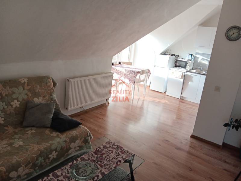 Viacgeneračný rodinný dom / investičná nehnuteľnosť – Dolná časť Zobor - Podkrovný priestor v rodinnom dome s kuchyňou, kvetinovou pohovkou a podlahou s dreveným dekorom.