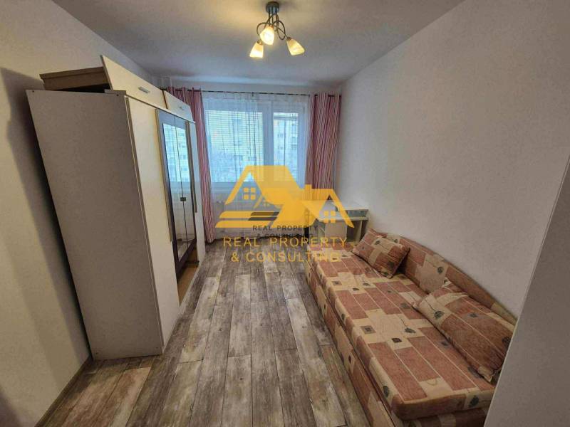 Prenajmem 3 izbový byt s loggiou v Nových Zámkoch - Izba v 3-izbovom byte s pohovkou, skriňou a podlahou s dreveným dekorom.