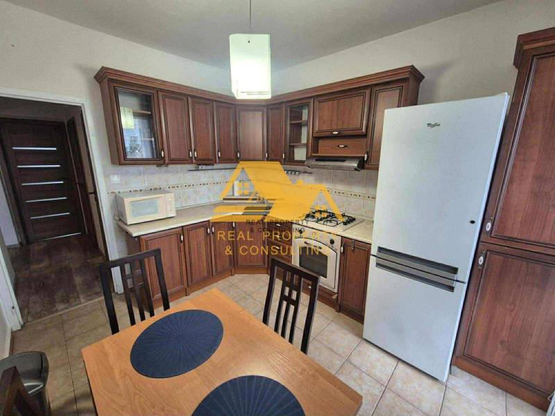 Prenajmem 3 izbový byt s loggiou v Nových Zámkoch - Kuchyňa s tmavým dreveným dekorom, sporákom a chladničkou v 3-izbovom byte.