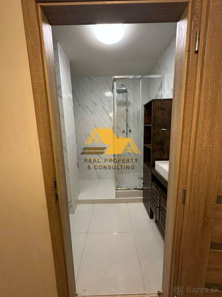 Prenajmem prerobený 2 izbový byt s balkónom v Nových Zámkoch - Kúpeľňa so sprchovým kútom a umývadlom v 2-izbovom byte, s obkladom vo svetlých tónoch.