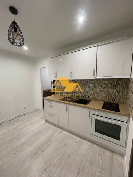 Prenajmem prerobený 1 izbový byt v Nových Zámkoch - Kuchyňa v 1-izbovom byte so svetlou linkou a podlahou s dreveným dekorom.