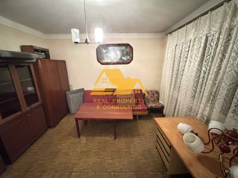 Predám rodinný dom s garážou v obci Dvory nad Žitavou - Izba v rodinnom dome s nábytkom, závesmi a podlahou s dreveným dekorom.