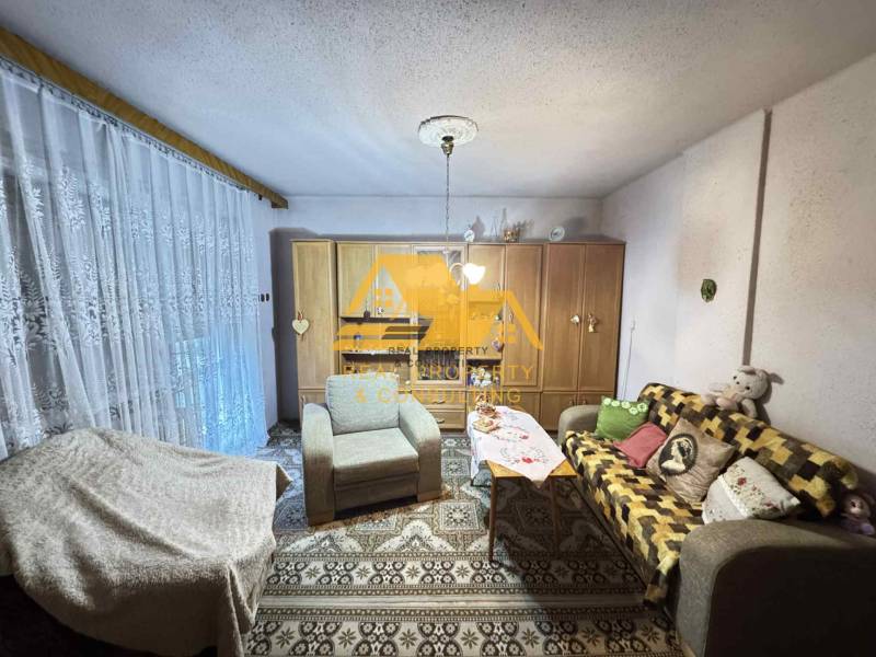 Predám rodinný dom s garážou v obci Dvory nad Žitavou - Obývacia izba v rodinnom dome s pohovkou, koberec a skrine s dekoráciami.