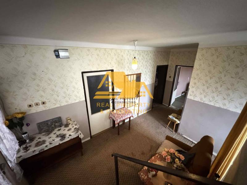 Predám rodinný dom s garážou v obci Dvory nad Žitavou - Interiér rodinného domu so vzorovanou tapetou, nábytkom a kvetinovou dekoráciou.