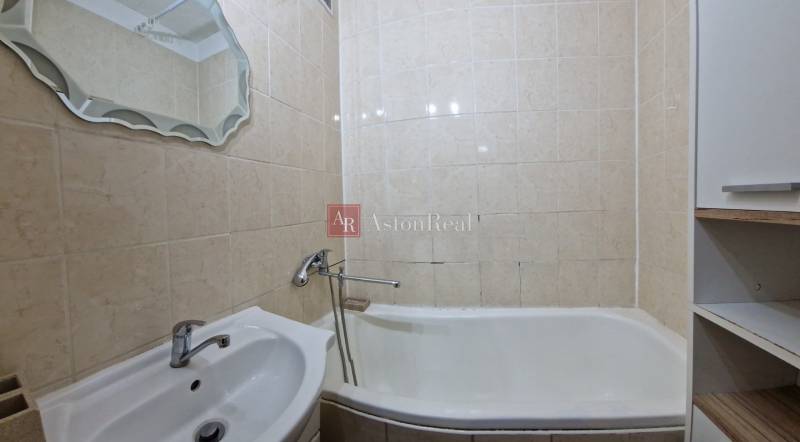 AstonReal:  predaj 2-izbový byt 54 m2, Poprad - Západ, Komenského - Kúpeľňa v 2-izbovom byte s vaňou, umývadlom a zrkadlom, obložená béžovými dlaždicami.