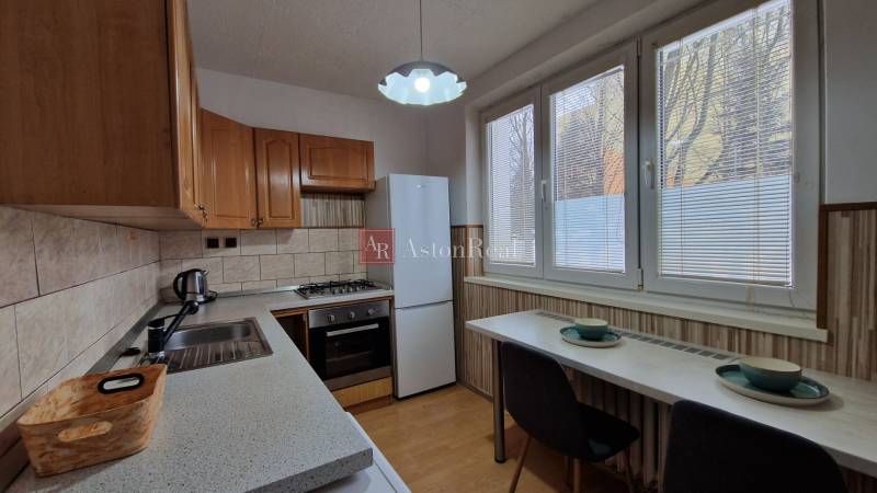 AstonReal:  predaj 2-izbový byt 54 m2, Poprad - Západ, Komenského - Kuchyňa v 2-izbovom byte so spotrebičmi a podlahou s dreveným dekorom.