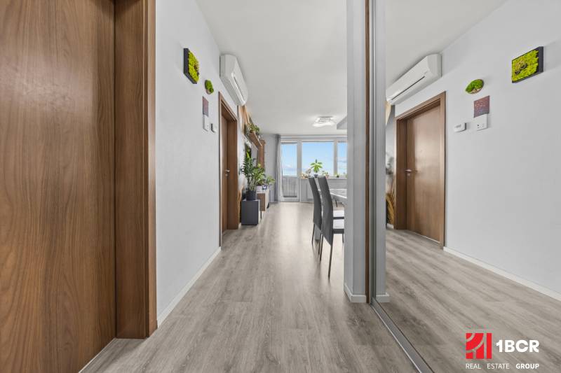 KOMPLETNE ZARIADENÝ 2-IZB. BYT,BALKÓN + PIVNICA,BUDATÍNSKA – PETRŽALKA - Interiér 2-izbového bytu s podlahou s dreveným dekorom, zrkadlom a klimatizáciou.