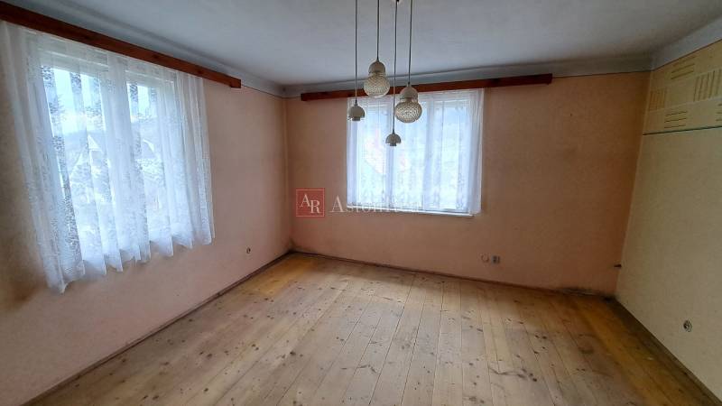 PREDAJ: Rodinný dom Kalameny s pozemkom 1.789m2 - Izba v rodinnom dome s dvomi oknami a podlahou s dreveným dekorom.