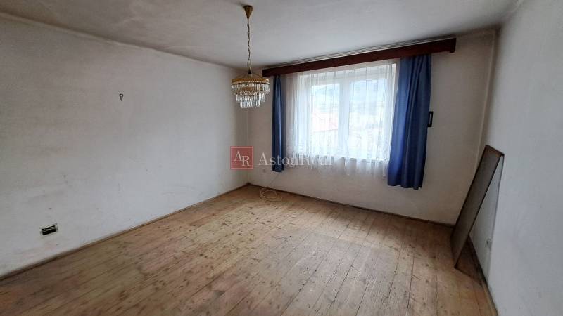 PREDAJ: Rodinný dom Kalameny s pozemkom 1.789m2 - Miestnosť v rodinnom dome s podlahou s dreveným dekorom, závesmi a lustrom.