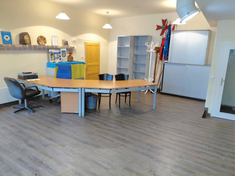 Prenájom kancelárie, Hauptstraße, Hauptstraße, Eisenstadt - Kancelárie s podlahou s dreveným dekorom, stolmi a stoličkami, dekorované vlajkami a predmetmi.