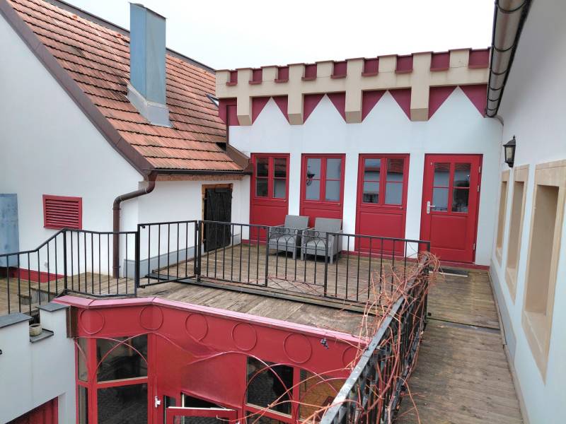 Prenájom kancelárie, Hauptstraße, Hauptstraße, Eisenstadt - Dvor s terasou a červenými dverami, obklopený architektúrou v Kanceláriách na Hauptstraße v Eisenstadte.