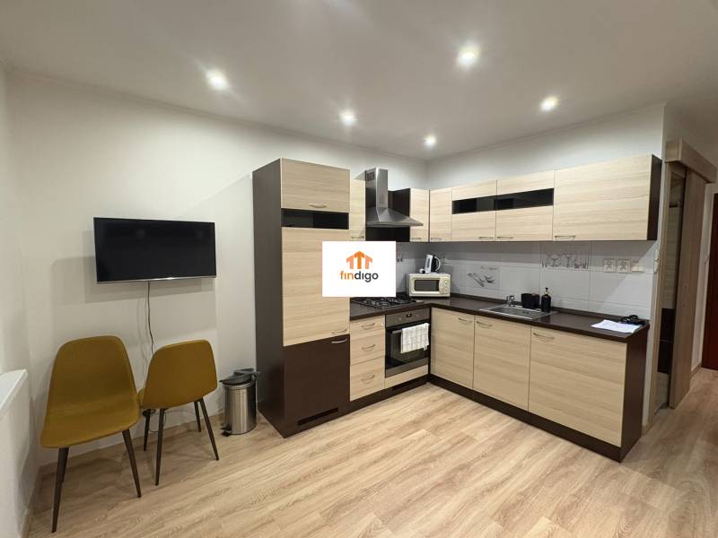 PRENÁJOM – 1-izbový byt po kompletnej rekonštrukcii, Šaľa – Bottova  - Kuchyňa v 1-izbovom byte s podlahou s dreveným dekorom a dvoma stoličkami.