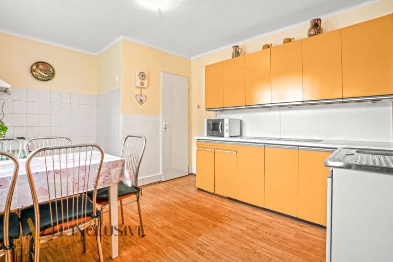 NA PREDAJ 4-IZBOVÝ RD NA VEĽKOM POZEMKU, VRAKÚŇ - Kuchyňa v rodinnom dome s oranžovými skrinkami a stolom na podlahe s dreveným dekorom.