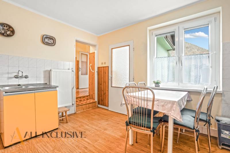 NA PREDAJ 4-IZBOVÝ RD NA VEĽKOM POZEMKU, VRAKÚŇ - Kuchyňa v rodinnom dome s podlahou s dreveným dekorom a stolom pri okne.