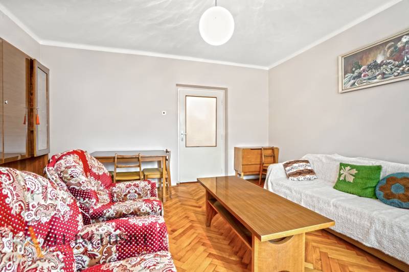 NA PREDAJ 4-IZBOVÝ RD NA VEĽKOM POZEMKU, VRAKÚŇ - Obývačka v rodinnom dome s červenými kreslami, dreveným stolíkom a podlahou s dreveným dekorom.