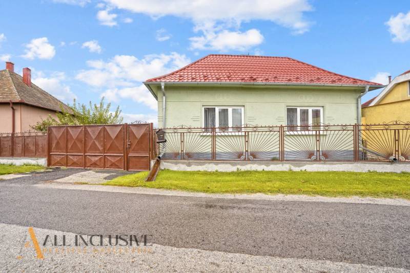 NA PREDAJ 4-IZBOVÝ RD NA VEĽKOM POZEMKU, VRAKÚŇ - Rodinný dom na Nekyje na Ostrove vo Vrakúni s červenou strechou a kovaným plotom.