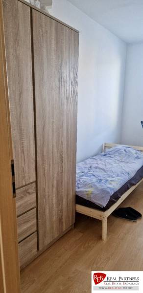 Prenájom 3 - izbový byt Bratislava - Petržalka - Jednolôžková posteľ a skriňa s podlahou s dreveným dekorom v 3-izbovom byte.