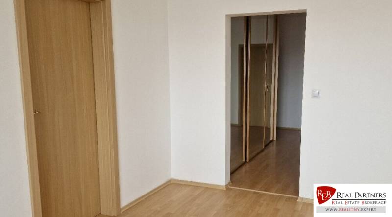 Prenájom 3 - izbový byt Bratislava - Petržalka - Izba s podlahou s dreveným dekorom a posuvnými zrkadlovými dverami v 3-izbovom byte.