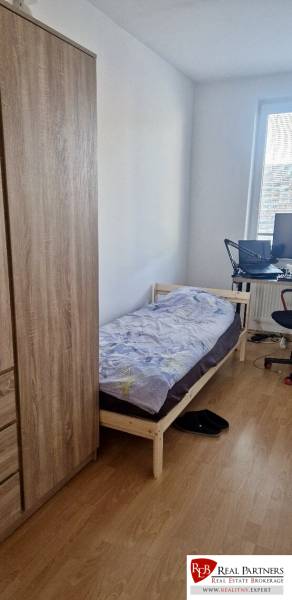 Prenájom 3 - izbový byt Bratislava - Petržalka - Spálňa v 3-izbovom byte s posteľou, skriňou a podlahou s dreveným dekorom.