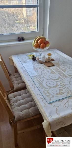 Prenájom 3 - izbový byt Bratislava - Petržalka - Jedálenský stôl v 3-izbovom byte s ovocnou misou a vzorovaným obrusom.