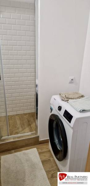 Prenájom 3 - izbový byt Bratislava - Petržalka - Kúpeľňa v 3-izbovom byte s práčkou, zrkadlom a podlahou s dreveným dekorom.