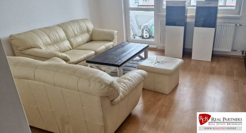 Prenájom 3 - izbový byt Bratislava - Petržalka - Sedacia súprava s podlahou s dreveným dekorom v obývačke 3-izbového bytu.