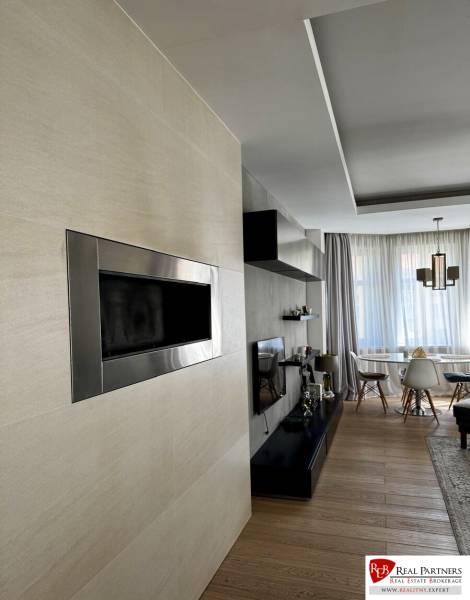 Prenájom veľkého luxusného 2izb bytu pri Bratislavskom hrade - Obývacia izba s krbom, televízorom a podlahou s dreveným dekorom v 2-izbovom byte.