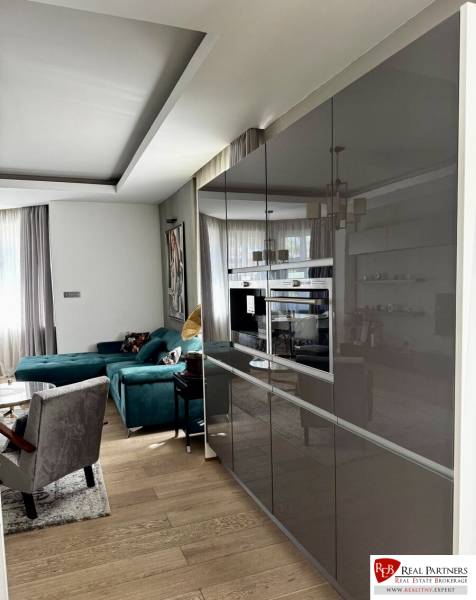 Prenájom veľkého luxusného 2izb bytu pri Bratislavskom hrade - Obývacia izba s tmavým nábytkom, pohovkou, zrkadlovými skriňami a podlahou s dreveným dekorom.