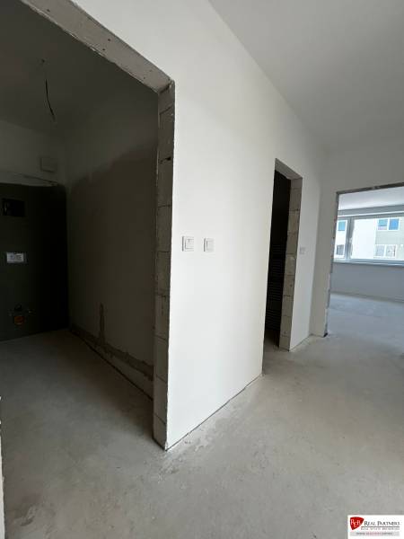 Predaj 3-izbového bytu len 15 minút od Bratislavy  - Nezariadený priestor v 3-izbovom byte s bielymi stenami a veľkým oknom.