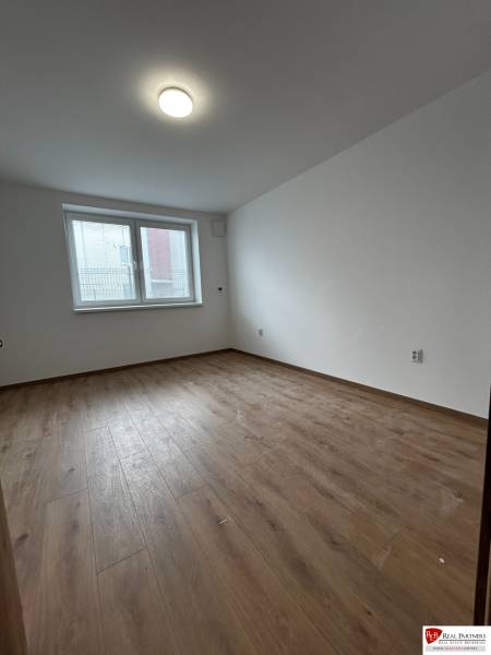 3-izbový byt v štandarde vrátane kuchyne len 15 minút od BA - Izba so svetlou podlahou s dreveným dekorom v 4-izbovom byte, veľké okno.