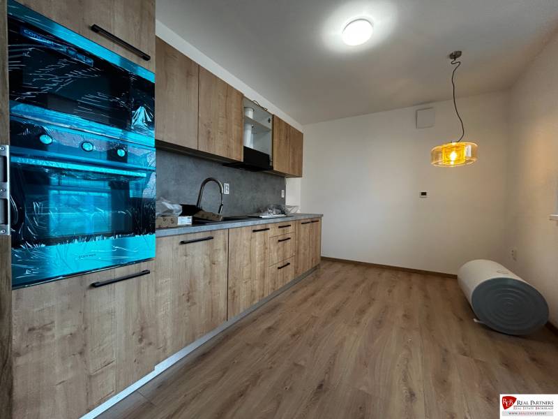 3-izbový byt v štandarde vrátane kuchyne len 15 minút od BA - Kuchyňa v 4-izbovom byte s podlahou s dreveným dekorom a zaveseným svietidlom.
