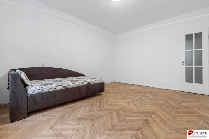 Predaj 4-izbový byt, 102m2, terasa 50m2, Bratislava-centrum, Gorkého - Izba s posteľou v 4-izbovom byte, podlaha s dreveným dekorom, svetlé steny.